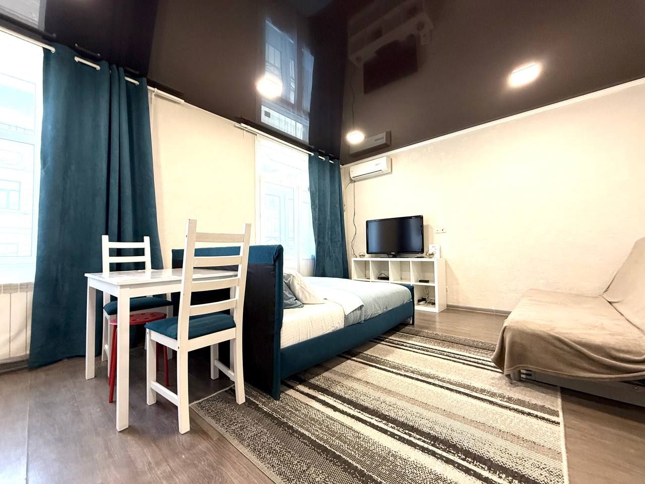 Вся студия 40 м²: обеденный стол, кровать, диван-кровать и телевизор